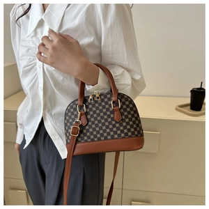 Detailopname van een vintage crossbodytas met geometrisch patroon en goudkleurig metaal