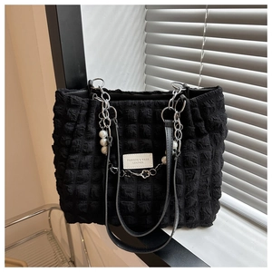 Detail of black popcorn texture tote with pearl charm and metal chain strap