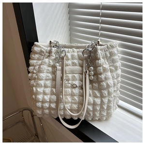 Close-up of cream textured bubble fabric tote bag with pearl flower chain charm
