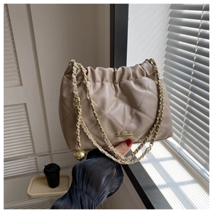 Close-up of beige quilted shoulder bag with gold chain and drawstring closure details
