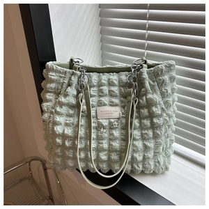 Detail of mint green tote bag featuring bubble pleated texture and metal chain strap