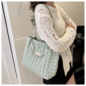 Détail du sac cabas vert clair à texture bulles avec chaîne argentée et perles décoratives