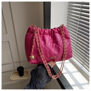 Detail of rose red quilted bucket bag with gold chain strap and metal ball charm