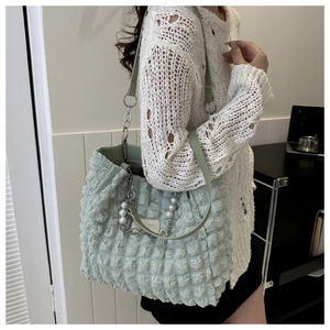 Détail du sac cabas vert clair à texture bulle avec une chaîne décorative en perles