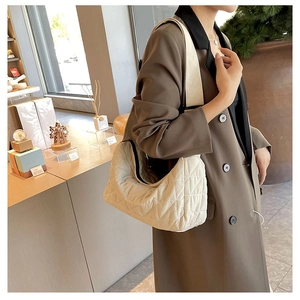 Detailed view of the quilted stitching on an off-white puffy pillow shoulder bag