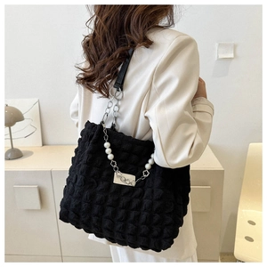 Détail du sac cabas noir à texture bulle avec chaîne décorative en perles et fleurs