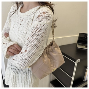 Beige quilted leather tote bag with gold chain strap shown on a model's shoulder