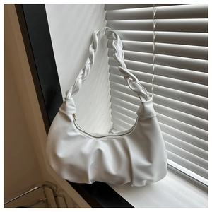 Detail of white pleated hobo bag with woven handle and metal zipper by a window