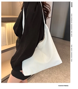 Detail of a large white PU leather tote bag with lychee texture on a model's shoulder