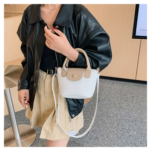 Mini white PU leather bucket bag with brown flap shown on model in a modern interior