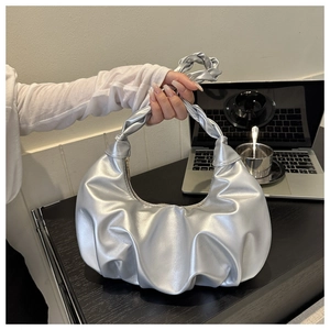 Close-up of a silver pleated dumpling bag with a stylish knotted handle on a table