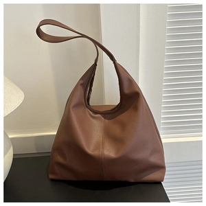 Close-up of brown pebbled leather tote bag with vertical stitching and hobo style detail