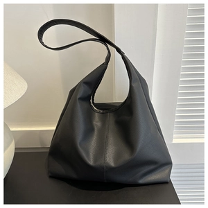 Detail of minimalist black pebbled leather hobo bag in a modern interior setting
