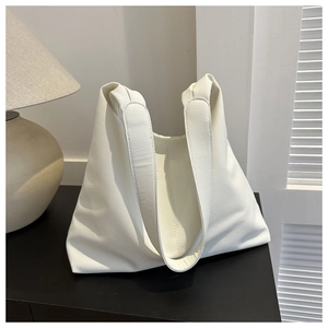 White lychee grain PU leather tote bag shown on a dark cabinet in a modern home setting