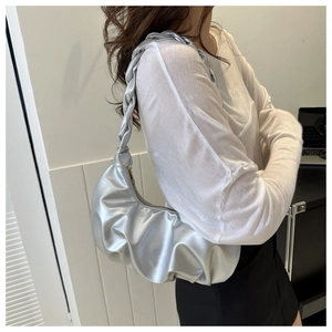 Silver pleated cloud bag with a braided handle shown from a side view on a model