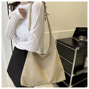 Detail of beige faux leather tote bag with pebble texture and wide shoulder strap