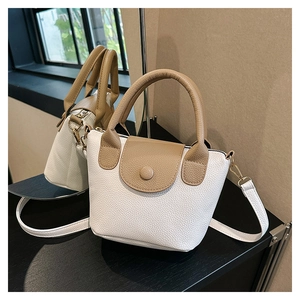 Detail view of mini two-tone PU bucket bag with white and brown lychee texture