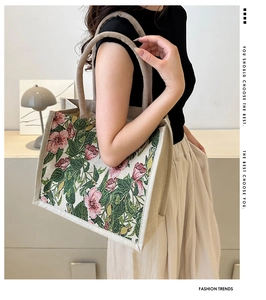 Detail of floral embroidery on a beige linen tote bag with sturdy woven handles