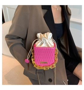 Close-up of pink matelassé leather bucket bag with chunky gold chain handle and drawstring