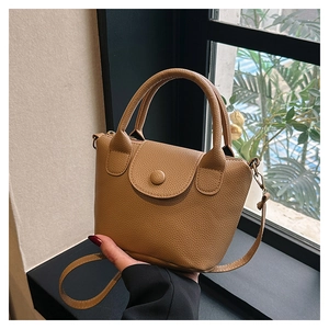 Detail shot of brown lychee texture PU leather bucket bag with top handle and strap