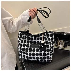 Detail of black and white tweed tote bag with leather chain strap and plush eye charm
