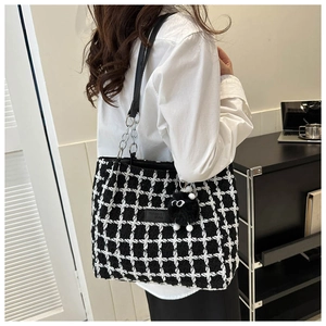 Fashionable black and white tweed tote bag with plush charm shown worn on shoulder