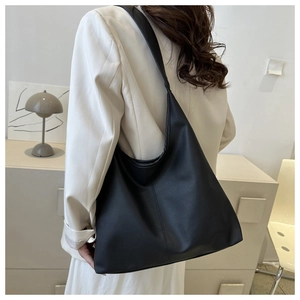 Close-up of black pebble grain PU leather tote bag worn by model in minimalist setting