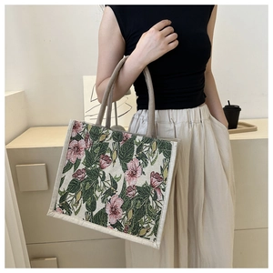 Detail of floral linen tote bag with vintage flower patterns and beige canvas handles