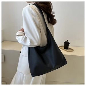Detailed view of black litchi grain leather hobo bag worn by a model in modern setting