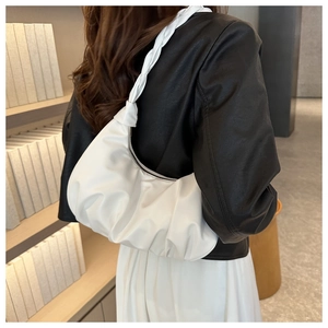 Detail of white pleated underarm cloud bag with unique knotted braided handle design
