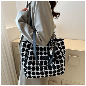 Close-up of large black and white checkered tote bag with leather strap and plush charm