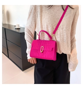 Detailed view of rose red crocodile embossed leather texture with gold metal clasp on handbag