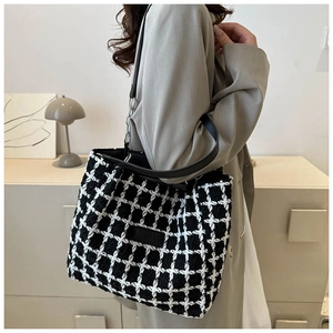 Detail of checkered tote bag featuring a leather strap with silver chain and chic fabric texture