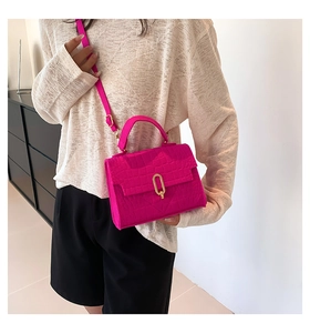 Detail of fuchsia shoulder bag featuring faux crocodile texture and golden metal clasp