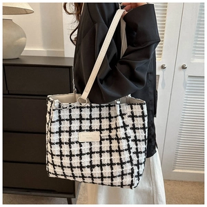 Detail of checkered tweed tote bag with white leather straps and fashion label
