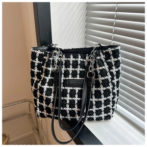 Detail view of monochrome plaid tote bag showing tweed texture and metal chain straps