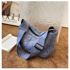 Detailed view of blue quilted nylon dumpling bag with diamond stitching and wide strap