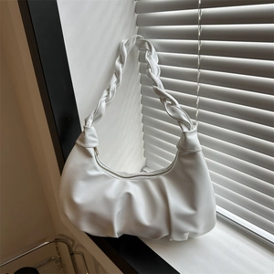White pleated hobo bag with woven handle on windowsill under natural louvre lighting