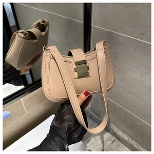 Dettaglio della borsa a tracolla beige con fibbia in metallo dorato e pelle liscia