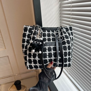 Fashionable black and white checkered tweed tote bag with leather handles and plush charm