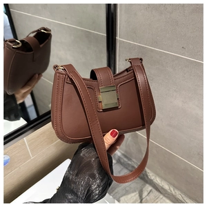 Dettaglio ravvicinato della borsa a sella in pelle marrone scuro con fibbia dorata
