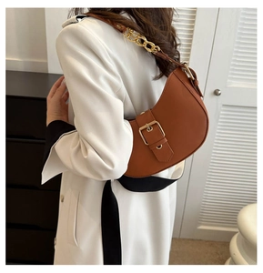 Detail of caramel brown hobo bag featuring large gold buckle and chic chain strap