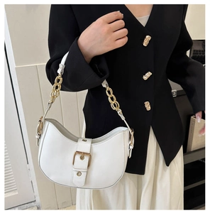 Detailed side view of white crescent shoulder bag with gold chain and buckle on model