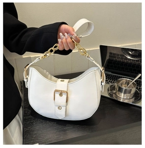 Close-up of white crescent shoulder bag featuring gold chain and buckle in modern setting