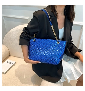 Detail of blue metallic patent leather tote featuring quilted pattern and gold chains