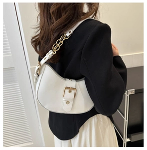 White crescent underarm bag featuring a chunky gold chain strap worn by a model