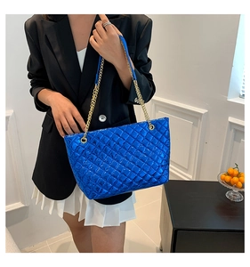 Model showing large electric blue quilted metallic tote bag with gold chain straps