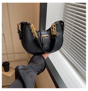 Close-up of black half-moon underarm bag with gold chain and metal buckle detail
