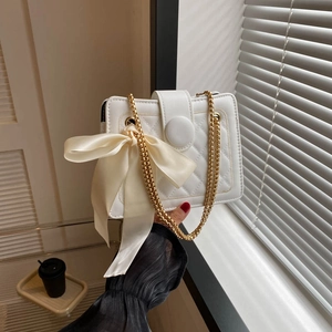 Elegant white quilted crossbody bag with gold chain strap and decorative silk bow