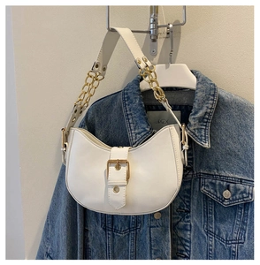 Détail du sac sous le bras en demi-lune blanc avec chaîne dorée sur veste en jean